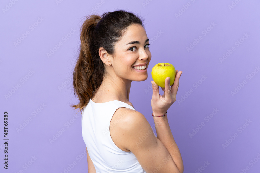 Woman over isolated purple background eating an apple Woman over isolated purple background eating an apple