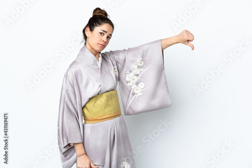 Woman wearing kimono over isolated background showing thumb down with negative expression
