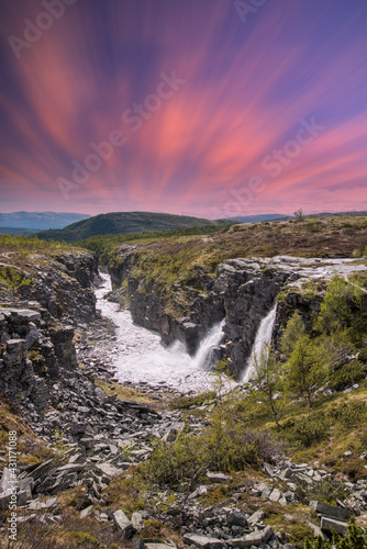 beautiful waterfalls with crystal clear water with mountains in the background at sunset Norway.