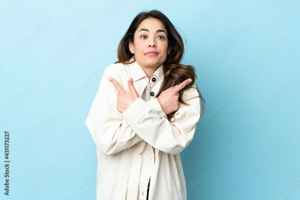 Woman over isolated background pointing to the laterals having doubts Woman over isolated background pointing to the laterals having doubts