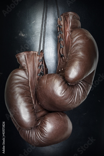 Brown leather boxing gloves lie on a black punching bag. Sport equipment. Training. The fight. Sparring                              © v75