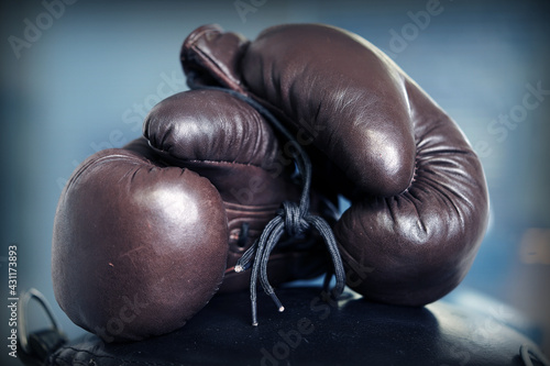 Brown leather boxing gloves lie on a black punching bag. Sport equipment. Training. The fight. Sparring 