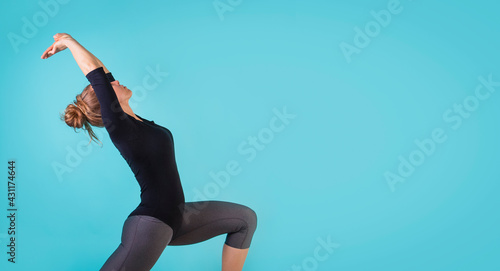 Attractive young woman working out, dancing on blue background. Athletic woman doing exercise. Strength and motivation, sport and healthy lifestyle, keep fit. Female fitness. Free space for text