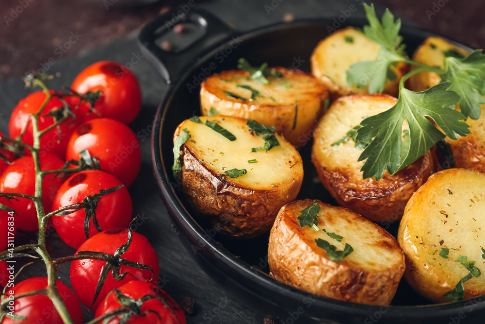 Frying pan of tasty fried potatoes with parsley and tomatoes on dark background Frying pan of tasty fried potatoes with parsley and tomatoes on dark background