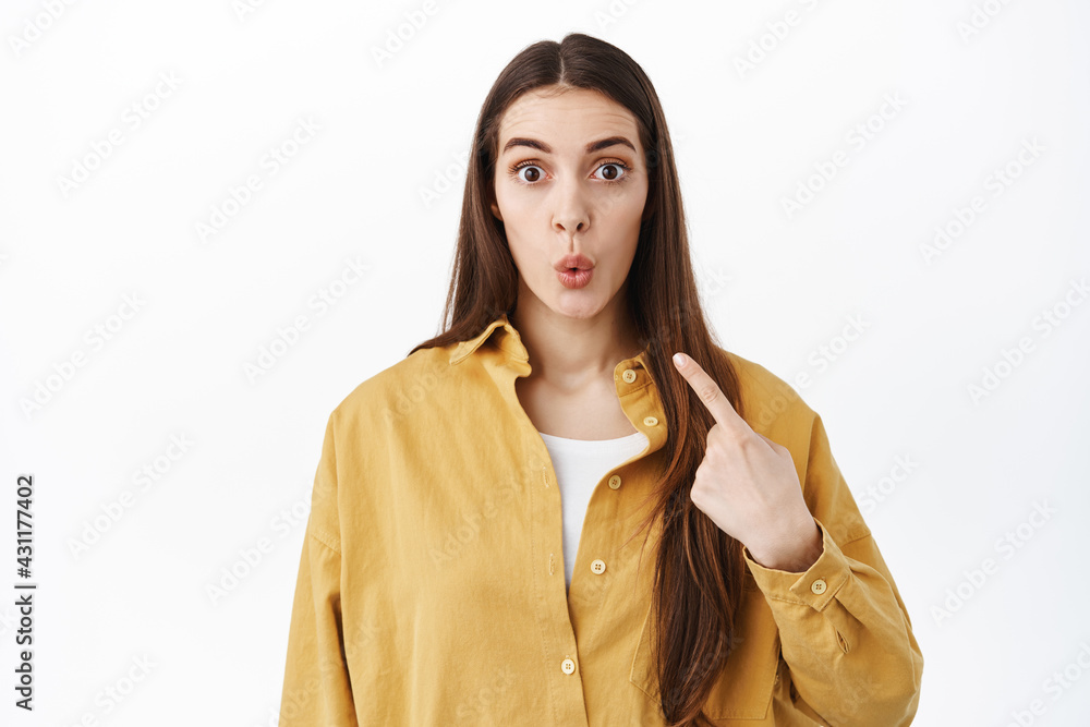 Is it me. Surprised and excited girl pointing at herself, winning or being chosen, picked from crowd, raise eyebrows and pucker lips curious, standing over white background Is it me. Surprised and excited girl pointing at herself, winning or being chosen, picked from crowd, raise eyebrows and pucker lips curious, standing over white background