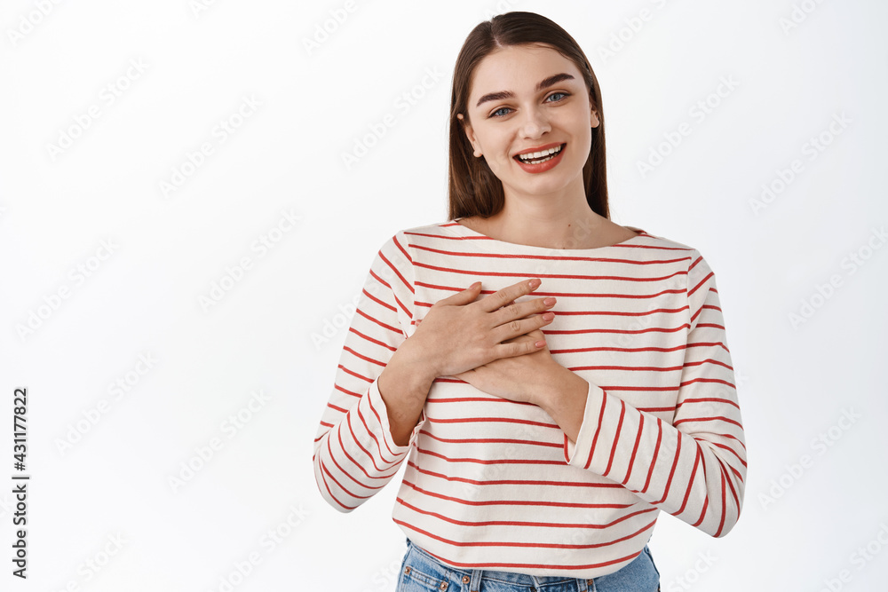 Thank you. Smiling heartfelt woman, feeling touched or flattered, holding hands on chest and looking grateful, express gratitude, appreciate, standing over white background Thank you. Smiling heartfelt woman, feeling touched or flattered, holding hands on chest and looking grateful, express gratitude, appreciate, standing over white background