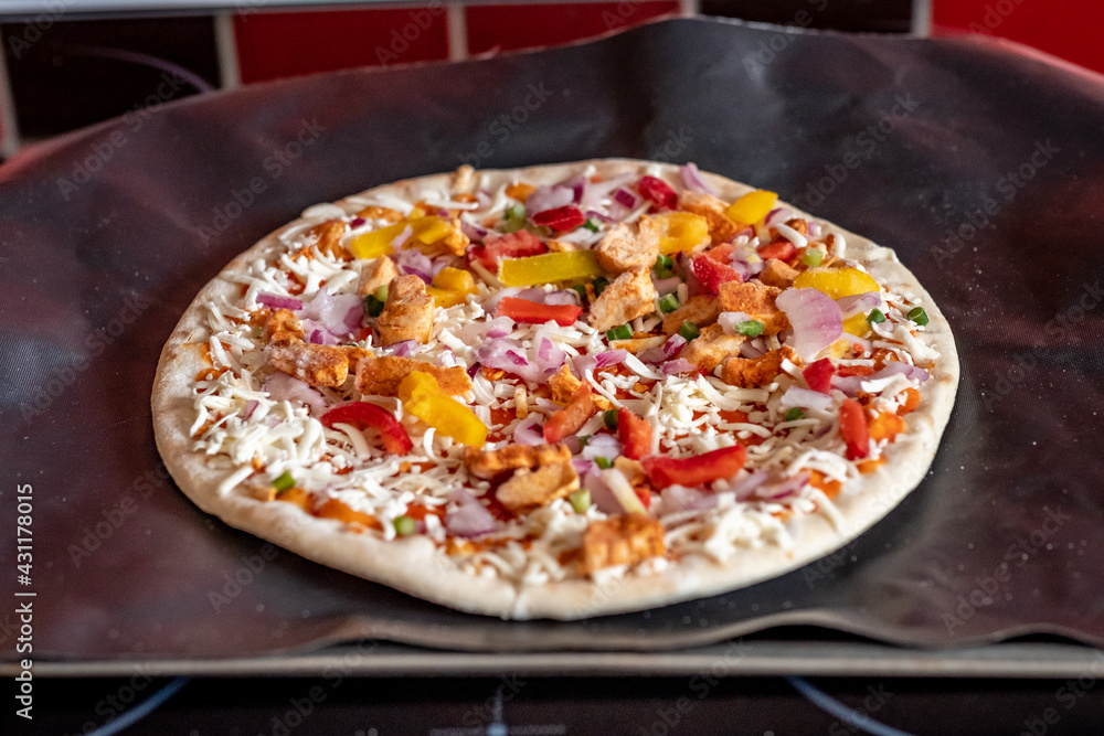 Close and selective focus of a readymade frozen stone baked thin sweet chilli chicken pizza on a baking mat ready to be cooked in the oven for Saturday night dinner Close and selective focus of a readymade frozen stone baked thin sweet chilli chicken pizza on a baking mat ready to be cooked in the oven for Saturday night dinner