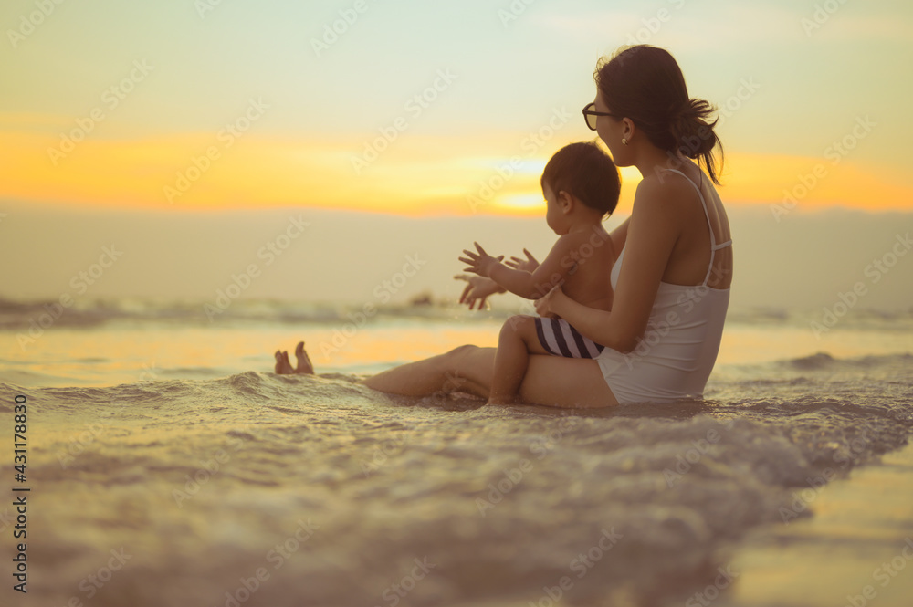 Happy family resting at beach in summer, Mother and som feet at the sea foam at the sunlight water is moving