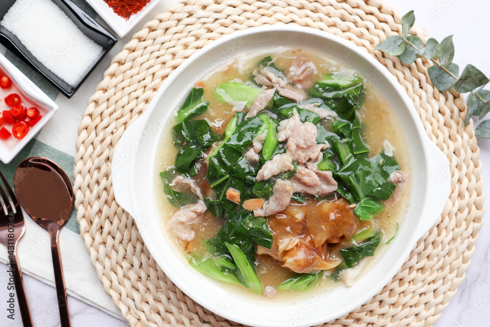 Stir Fried noodle with pork and kale in gravy sauce (Thai food called Rad Na Moo) - Top view with seasoning on marble background Stir Fried noodle with pork and kale in gravy sauce (Thai food called Rad Na Moo) - Top view with seasoning on marble background