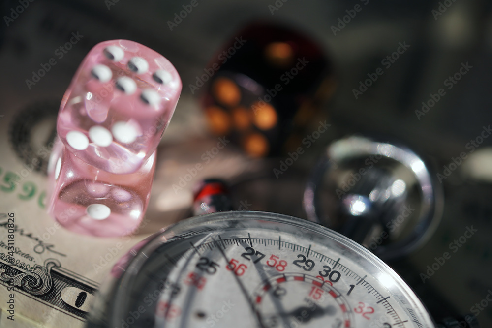 A stopwatch and two dice lie on a layer of money close-up. Game, leisure, entertainment, competition. Chronograph                               