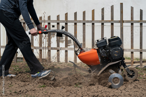 A young man digs the ground in the garden with a motorcultivator photo