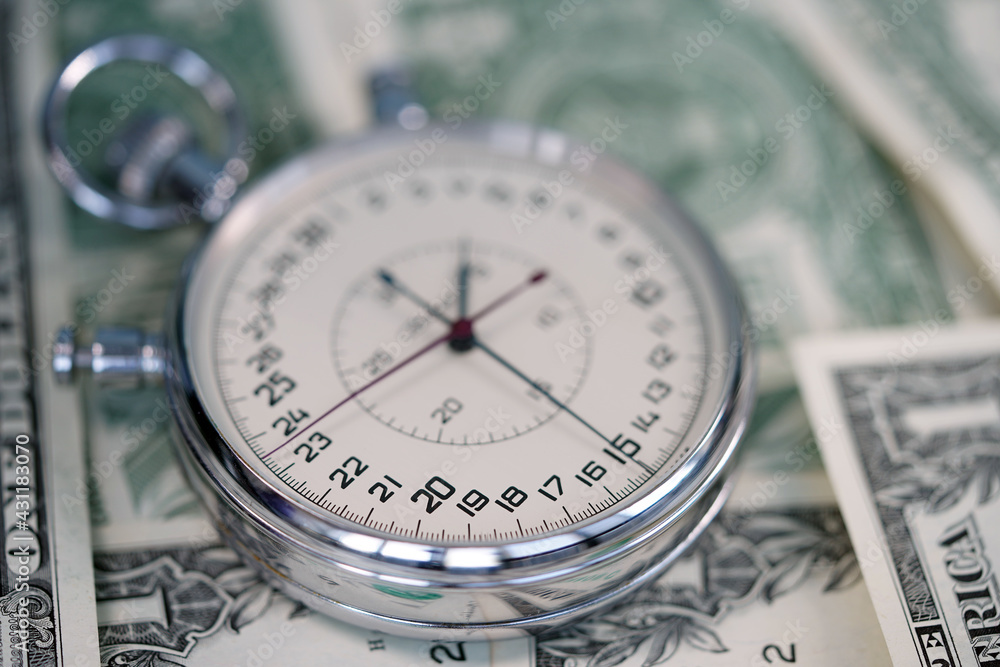 Time is money. Dollar close up. Money macro shot. The stopwatch lies on the dollars. Chronograph. Measurement. Rapidity Force Speed. Time is money. Dollar close up. Money macro shot. The stopwatch lies on the dollars. Chronograph. Measurement. Rapidity Force Speed.