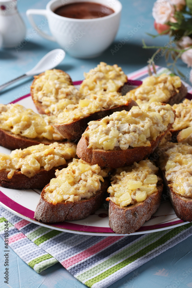 Baked homemade toasts with chicken, cheese, pineapple and garlic as well cup of coffee on a light blue background. Baked homemade toasts with chicken, cheese, pineapple and garlic as well cup of coffee on a light blue background.