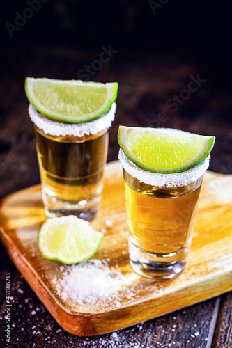 glasses of Mexican Gold Tequila with lemon and salt on wooden background