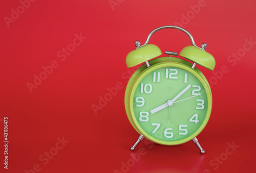 Close-up of retro green alarm clock over red background.