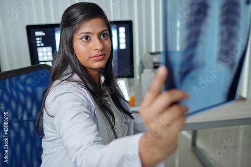 Pretty young Indian radiologist examining chest x-ray of patient being treated for coronavirus