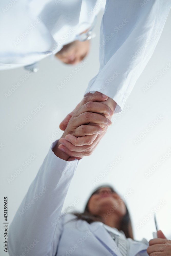 Chief physician greeting new general practitional and shaking her hand, view from below