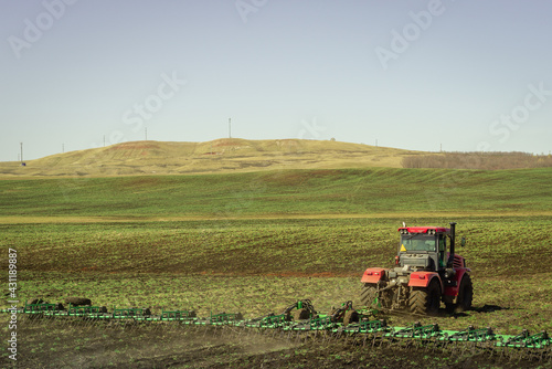 The tractor works on a green field.