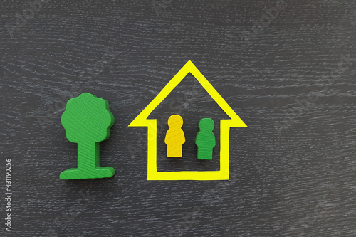 A house  two figures of green and yellow people on a dark background. Real estate  joint ownership  housing.