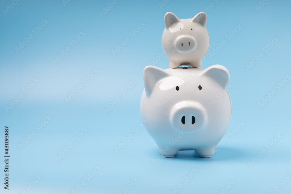 Finance, saving money. Stack two white piggy banks on blue background with copy space. Concept savings, investment, save money in future.
