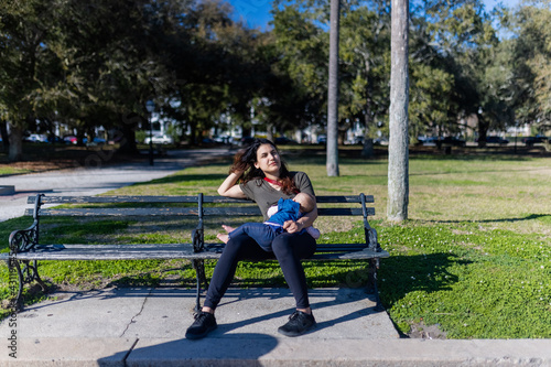 Beautiful mother sitting on bench and breastfeeding her cute baby © Christian