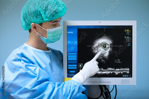 Blurred doctor used Intravascular ultrasound imaging (IVUS) machine ( focus at screen) at cardiac catheterization laboratory room
