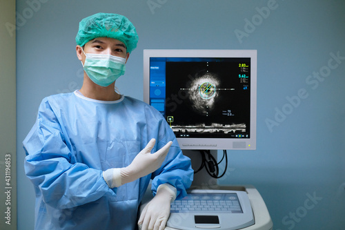 Doctor wears sterile uniform and uses Intravascular ultrasound imaging (IVUS) machine at cardiac catheterization laboratory room photo