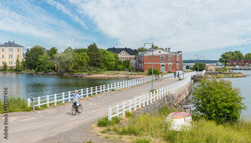 Helsinki . Beautiful panorama of the island of Suomenlinna . The ancient fortress of Suomenlinna. Sights of Helsinki. A girl rides a bicycle. Tourists walk on the bridge .