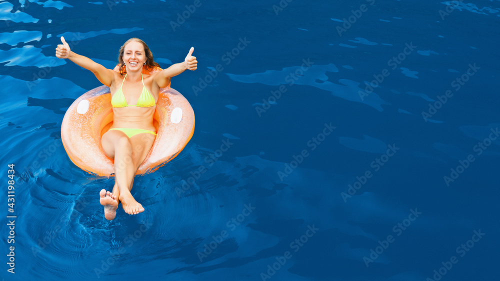 Photo of young woman swimming with fun on inflatable floating ring in sea water pool. Family travel lifestyle, kids with parents outdoor swimming activity on summer holidays at tropical beach resort