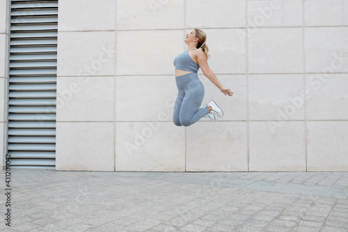 Happy excited plus size young woman jumping high up in the air © DragonImages