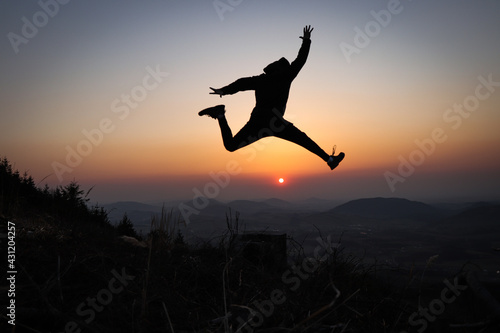Wallpaper Mural Silhouette of a teenager and an athlete trains explosiveness and tries to jump as high as possible at sunset in the European mountains. Training in natural conditions. Self weight training Torontodigital.ca