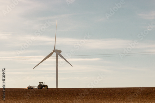 champ avec tracteur devant une éolienne photo