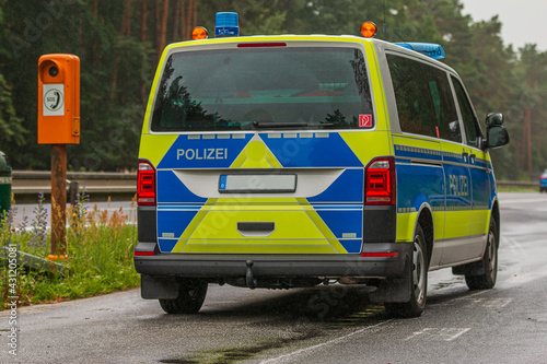 German police car in an emergency stopping bay on a motorway in the state of Brandenburg from a side view. Emergency telephone on the roadside. two-lane highway with asphalt surface in rainy weather