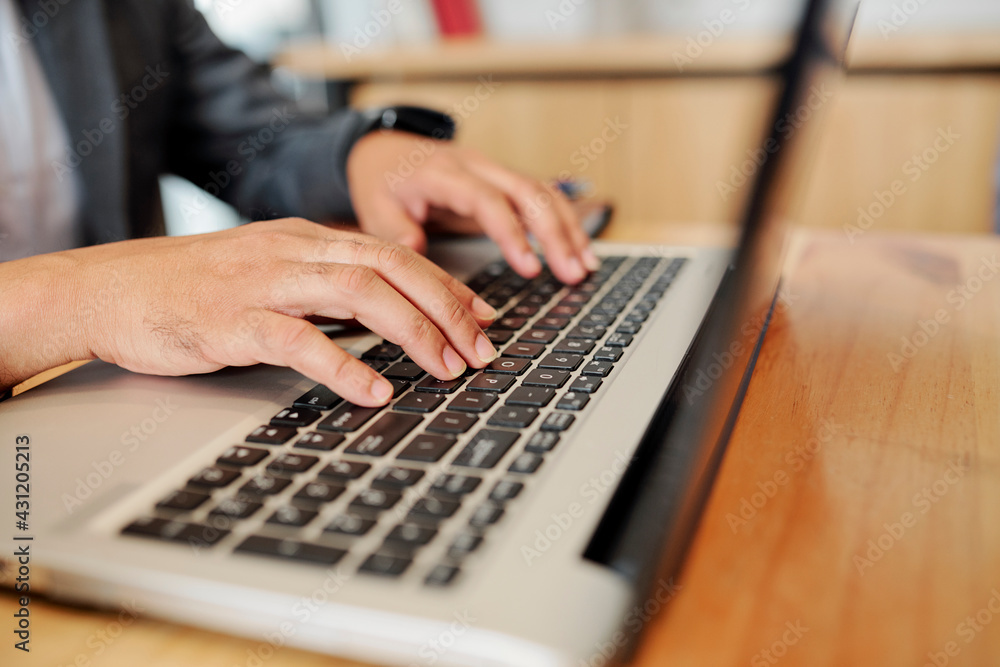 Hands of man sitting at office desk and programming on laptop or working on monthly report Hands of man sitting at office desk and programming on laptop or working on monthly report