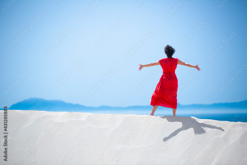 happy woman with a red dress on a white sandy beach