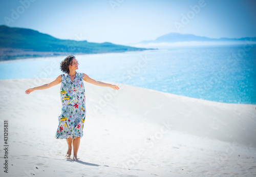happy woman with a colored dress on a white sandy beach