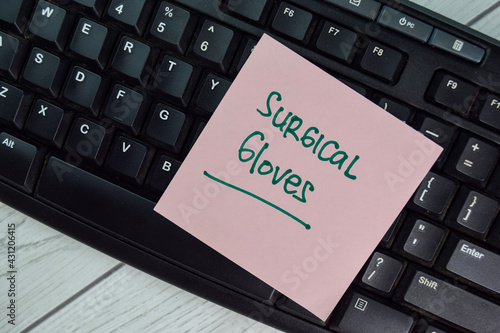 Surgical Gloves write on sticky notes isolated on Wooden Table.