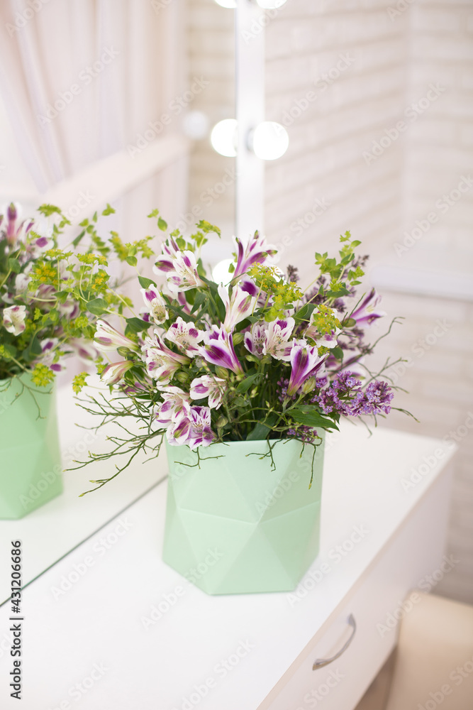 Fototapeta premium Beautiful flower bouquet in vase on table in beauty salon, mirror reflection