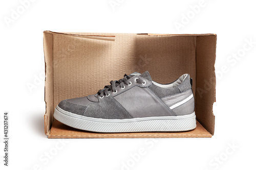 Grey casual sports shoes/sneaker in a brown cardboard box isolated on a white background