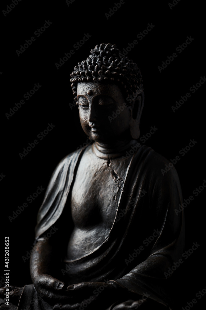 Meditating Buddha Statue on dark background. Copy space.