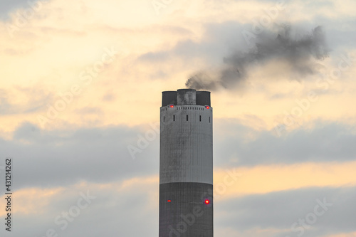 Power station industrial chimney with smoke at sunset. Global warming pollution emitting industrial greenhouse gasses whilst generating electricity.