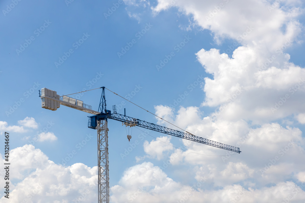 Tower Crane in the clouds and blue sky. The Crane tower in construction site of a high-rise condominium. High cranes on the construction site