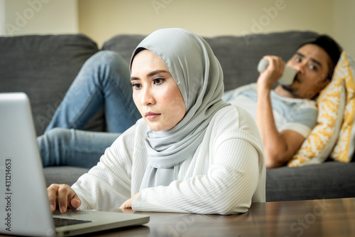 Photography stress looking wife work with her laptop and husband at the sofa