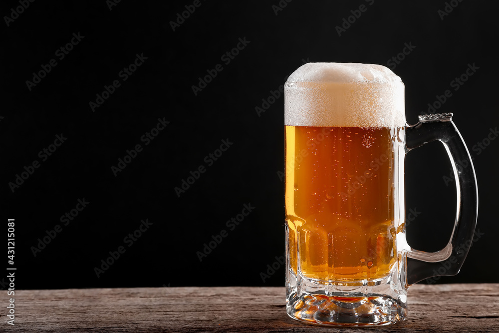 Pouring a glass of brown beer on a rough wooden table