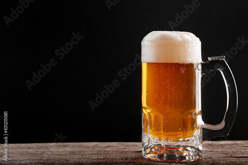 Pouring a glass of brown beer on a rough wooden table