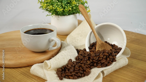 Fresh hot black coffee with robusta coffee beans and home decoration on wooden table