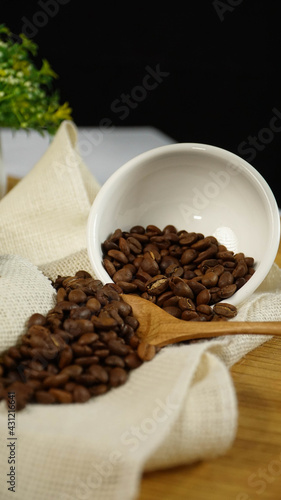 Brown coffee beans on white small bowl in dark background