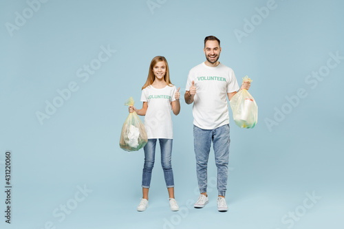 Full length two young friends couple teen girl man wear white tshirt green volunteer hold bag trash walk isolated on pastel blue color background Voluntary free team work help charity grace concept