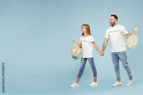 Full length two young friends couple teen girl man wear white tshirt green volunteer hold bag trash walk isolated on pastel blue color background Voluntary free team work help charity grace concept