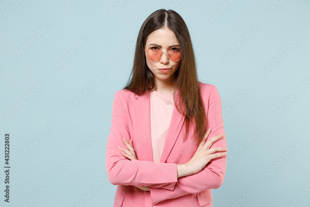 Young serious disappointed displeased dissatisfied caucasian woman 20s in pastel pink clothes glasses hold hands crossed folded isolated on blue background studio portrait. People lifestyle concept. Young serious disappointed displeased dissatisfied caucasian woman 20s in pastel pink clothes glasses hold hands crossed folded isolated on blue background studio portrait. People lifestyle concept.